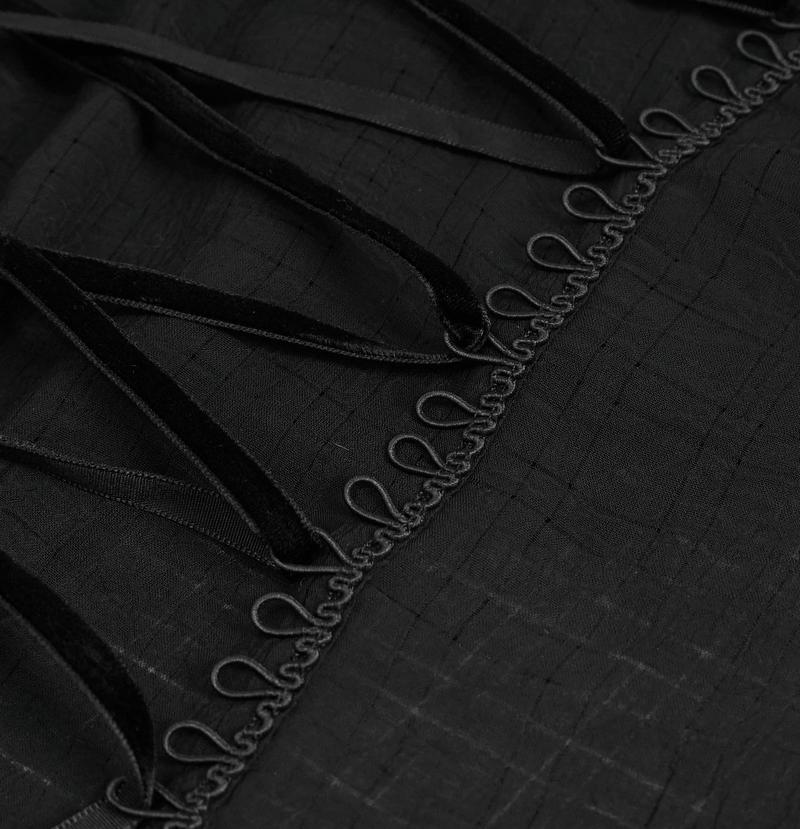 Close-up of lace-up detailing featuring black ribbons on a gothic style women's long sleeve top.