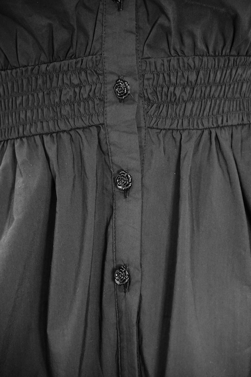 Black off-shoulder blouse with decorative rose buttons and smocked bodice detail.