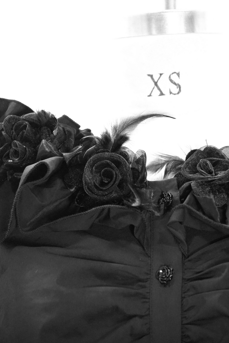 Close-up of women's gothic off-shoulder blouse with rose flowers and flare sleeves in black, showcasing trendy details.