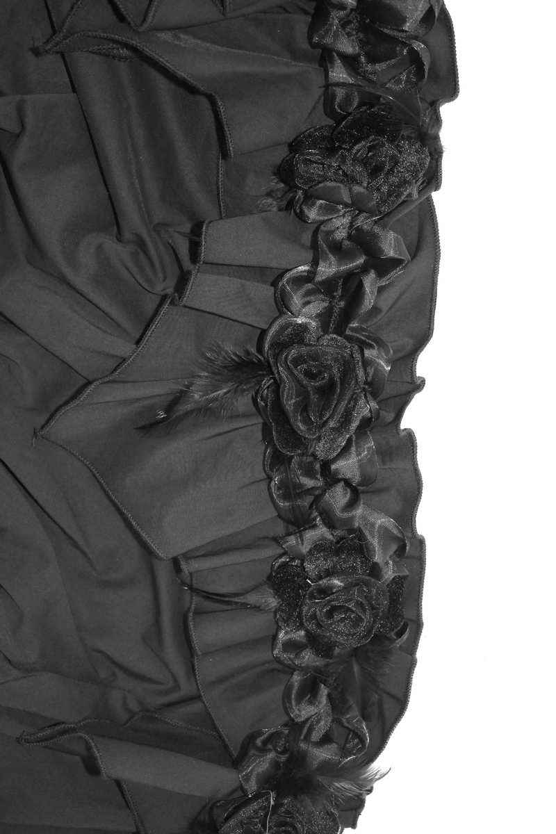 Close-up of black fabric adorned with elegant rose flowers and ruffles for a gothic blouse design.