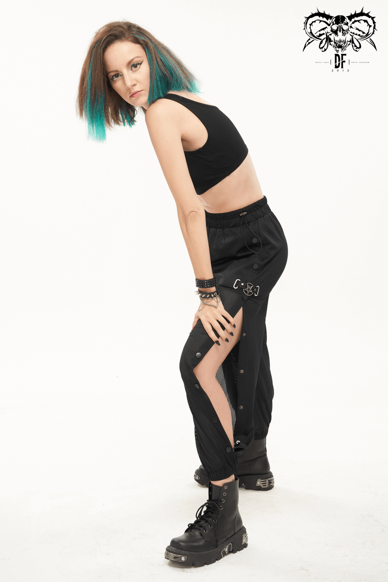 Trendy woman in black mesh buttoned jogger pants with punk side openings, styled with a crop top and bold accessories.