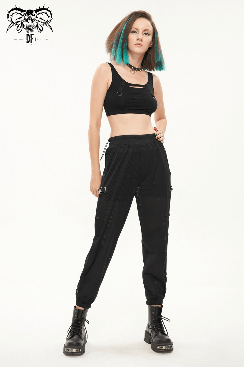 Stylish woman in black mesh buttoned jogger pants and crop top, showcasing a trendy punk look.