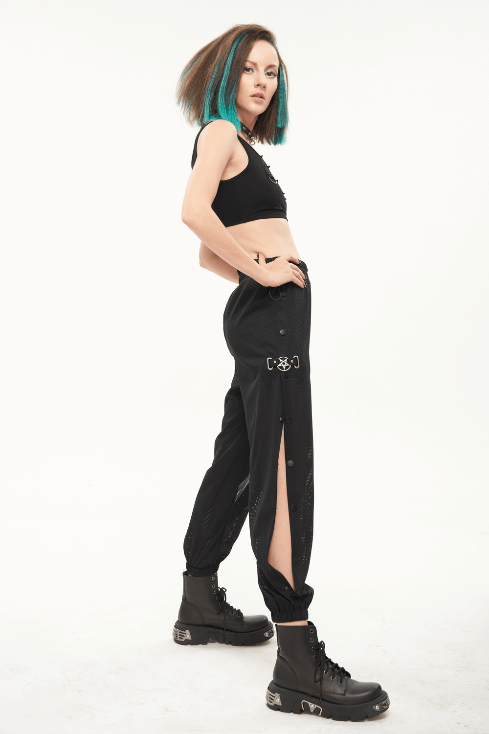 Stylish woman in black mesh jogger pants with punk side openings and combat boots, showcasing trendy urban fashion.