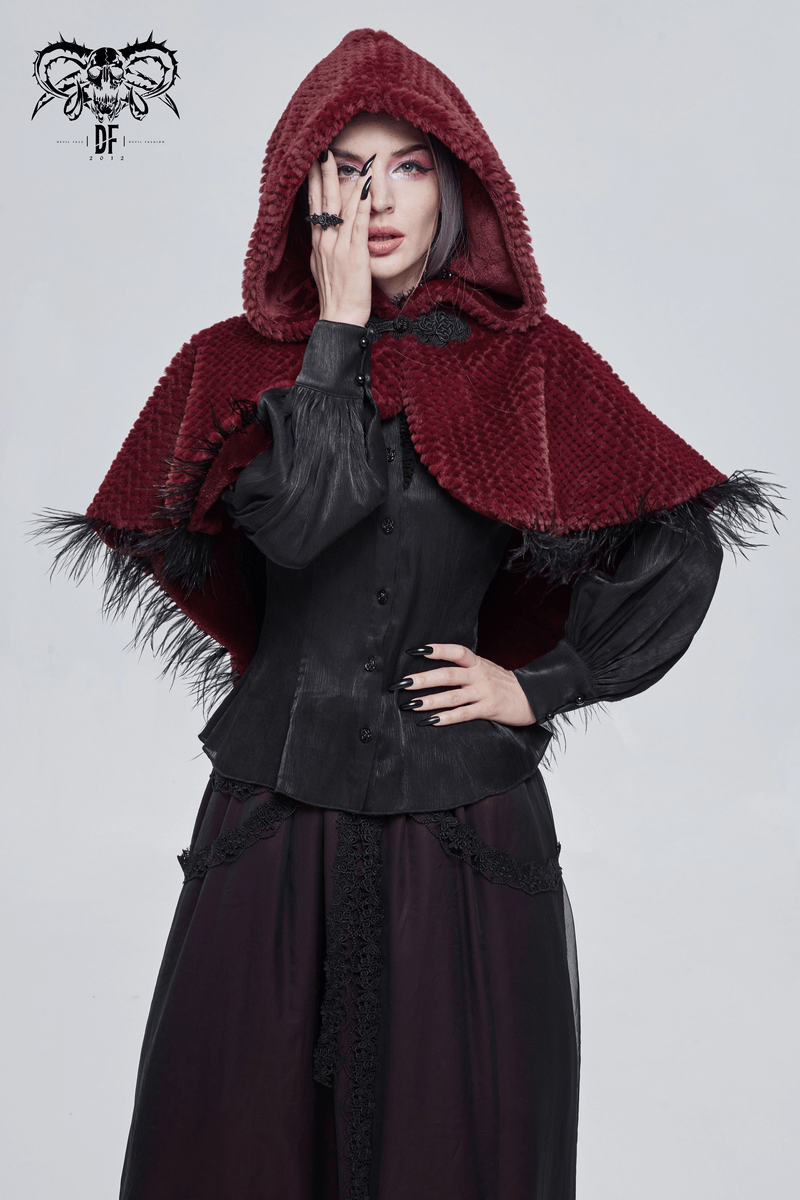 Stylish woman in a red hooded short cape with fringes, showcasing gothic fashion.