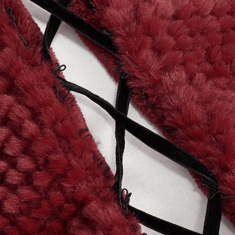 Close-up of the red plush fabric and intricate lacing details of a women's hooded cape with fringes.