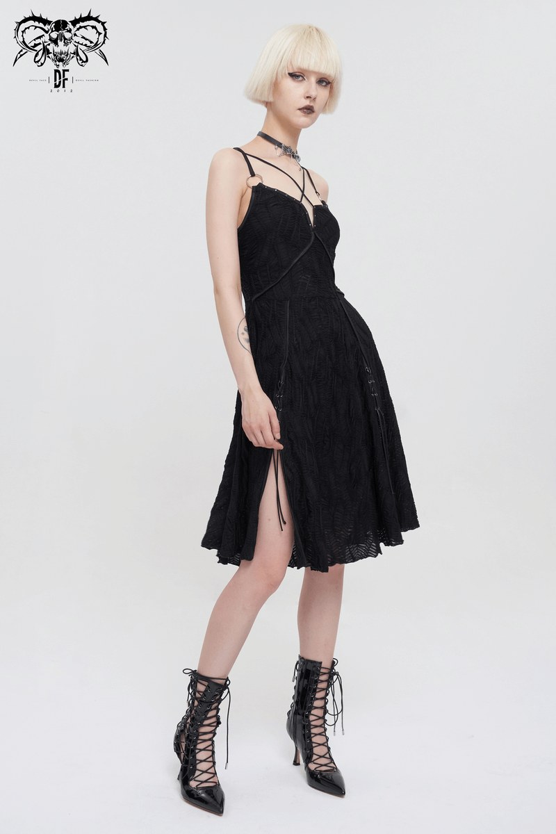 Stylish woman in a black gothic punk short dress with slit hem and cross straps, showcasing edgy fashion.