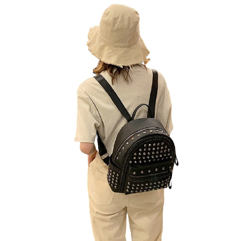 Stylish black casual backpack with metal rivets, perfect for a gothic look, worn with a bucket hat.