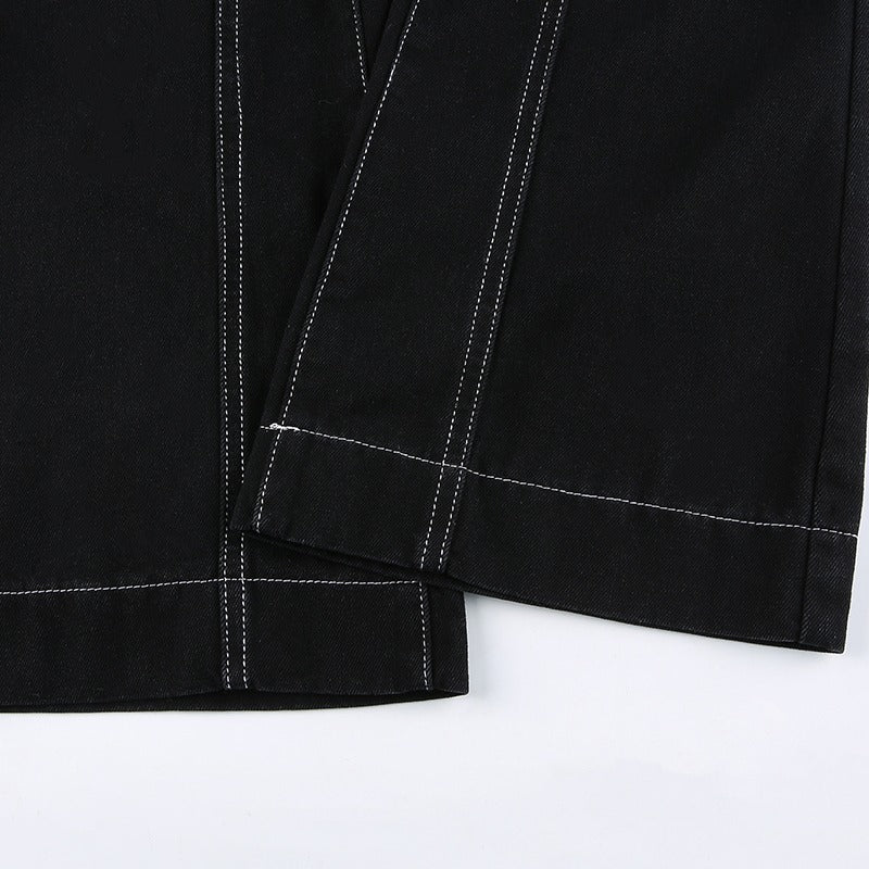 Close-up of black high-waisted trousers featuring white stitching details and smooth fabric texture.