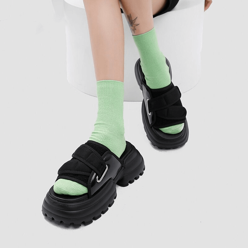 Women wearing black thick platform sandals with green socks, perfect for summer beach outings.
