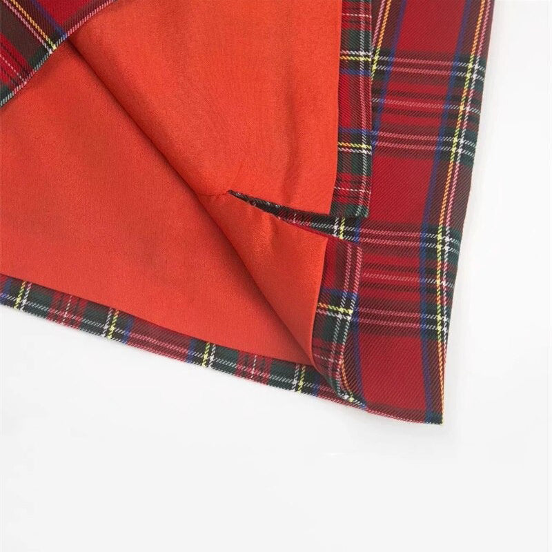 Close-up of red plaid fabric with orange lining, showcasing the stylish hem of a chic pencil skirt.