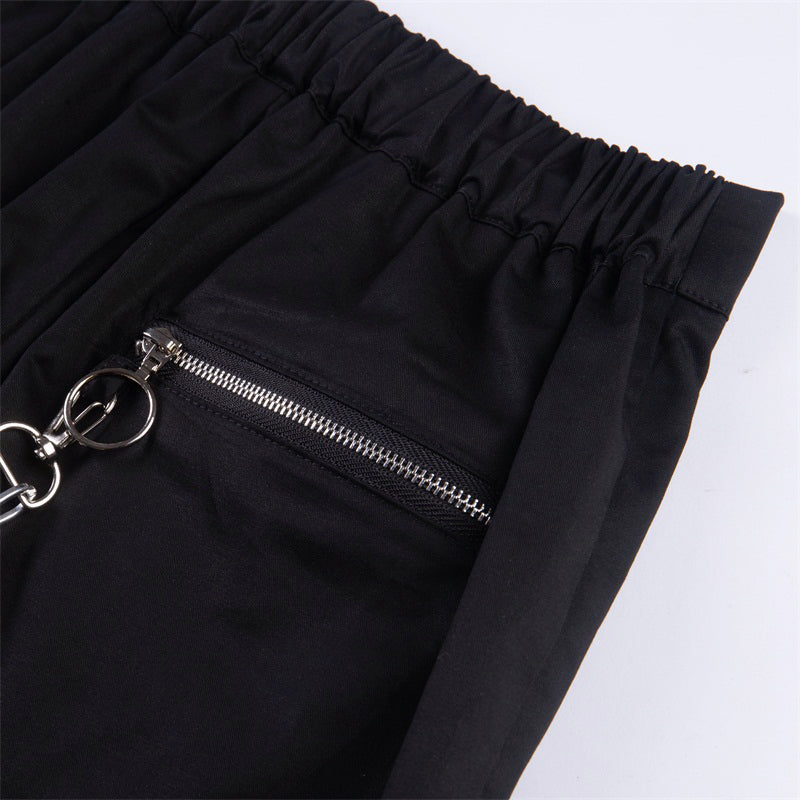 Close-up of solid black streetwear pants featuring zipper pocket and chain detail, perfect for gothic fashion lovers.