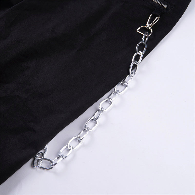 Close-up of stylish black women's streetwear pants featuring a trendy metallic chain detail.