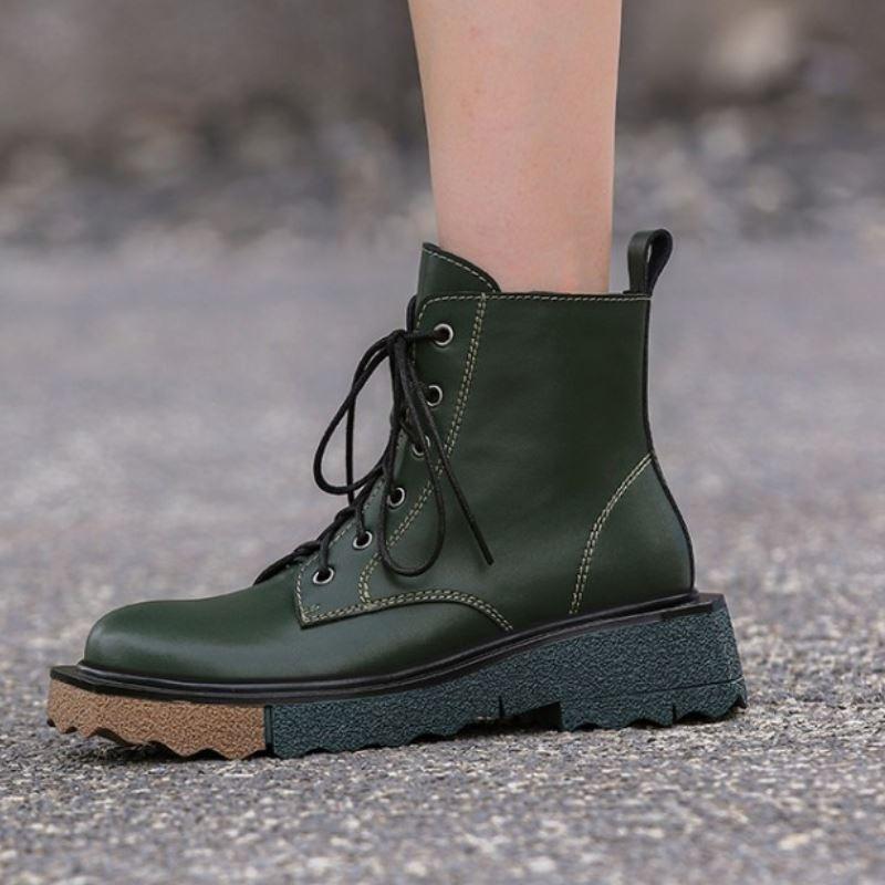 Stylish women's ankle boots in dark green leather with lace-up design and durable sole, perfect for trendy outfits.