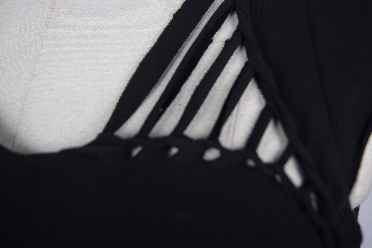 Close-up of the intricate asymmetrical cut and slashed design on a black gothic punk top.