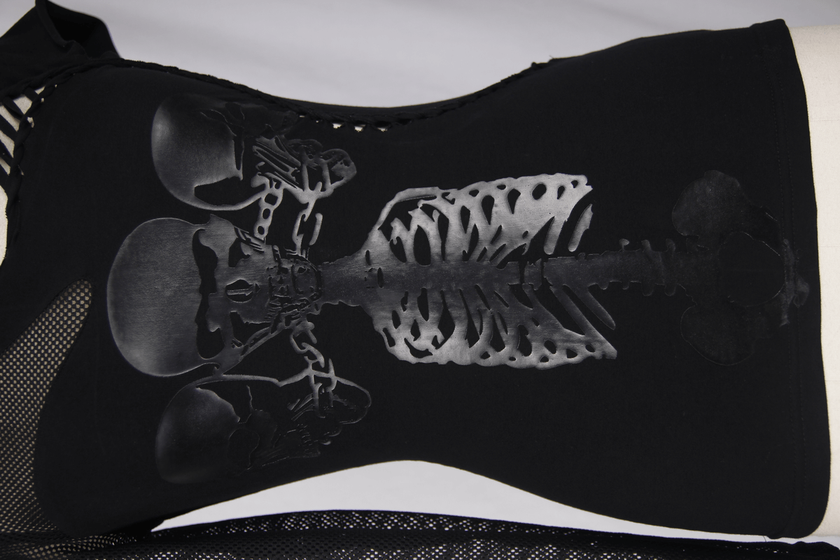 Close-up of black asymmetric women's top with skeleton print, gothic punk style fashion.