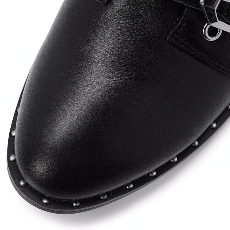 Close-up of women's black ankle boot with low heel, featuring metal rivets and stylish buckle detail.