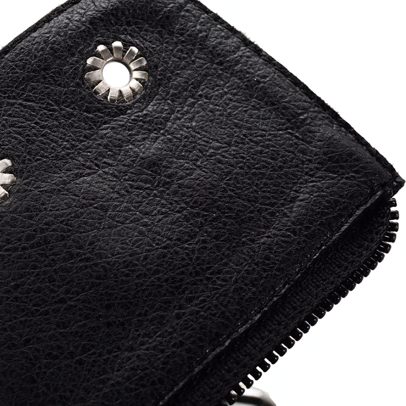 Close-up of black ankle boot with metal rivets and zipper detail, showcasing stylish rock-inspired design.