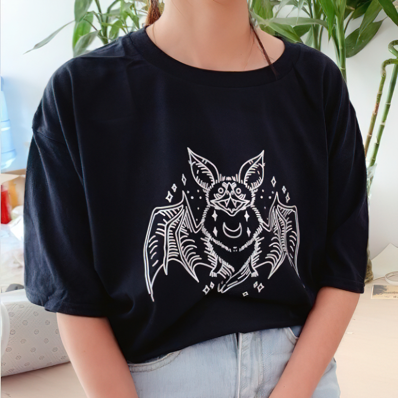Stylish women's bat graphic t-shirt in gothic style, featuring a white bat print on a black loose-fit shirt.
