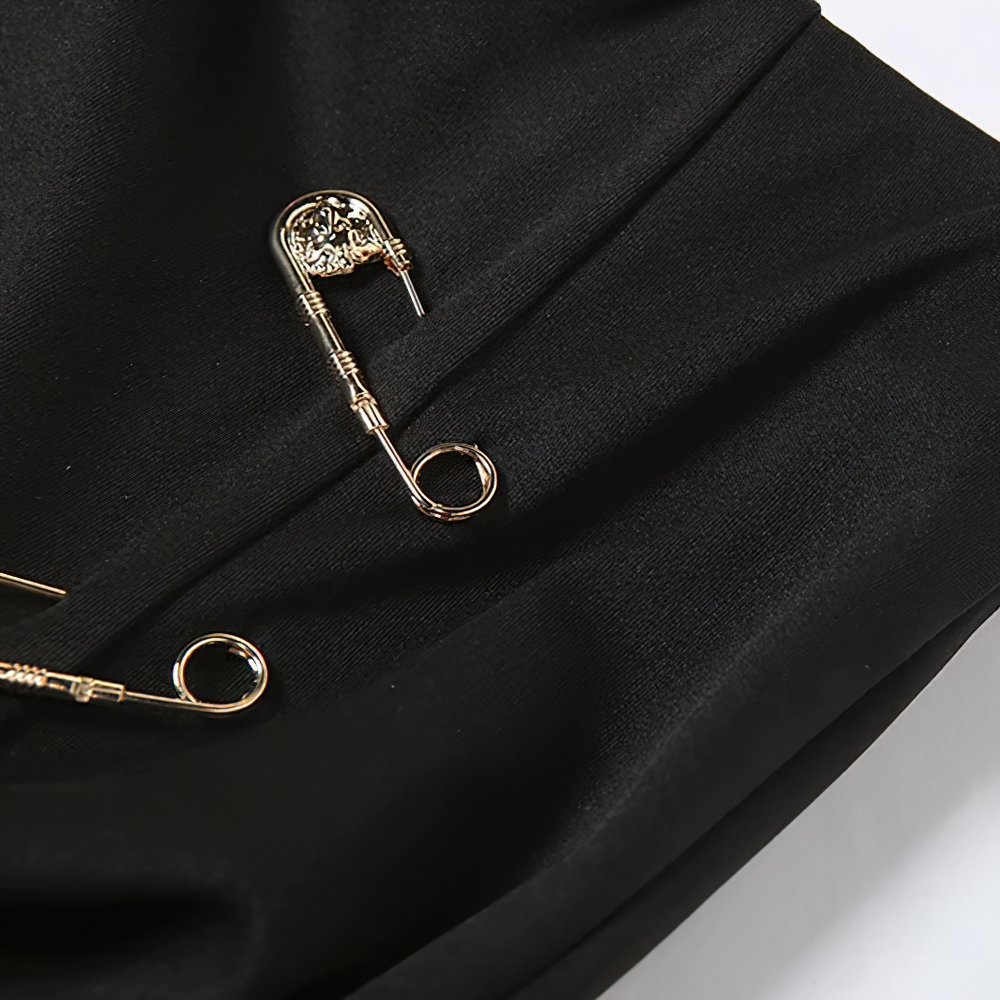 Close-up of black fabric with decorative gold safety pins, perfect for gothic fashion enthusiasts.