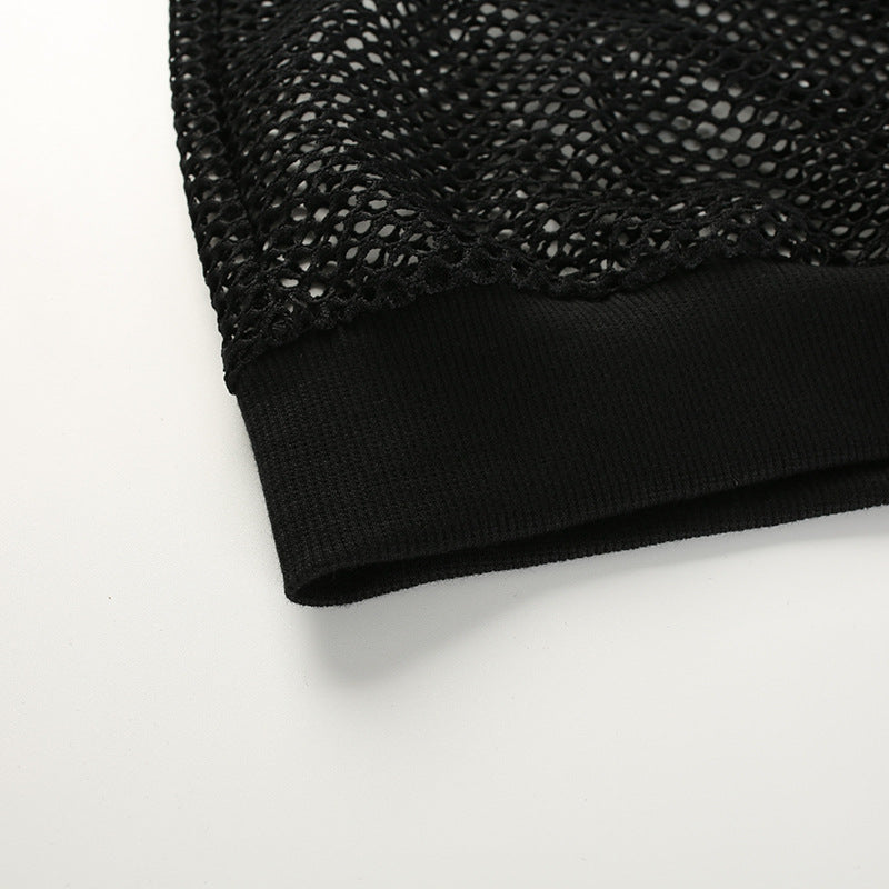 Close-up of the hem of a women's black mesh crop top, featuring textured mesh fabric and a smooth black cuff.