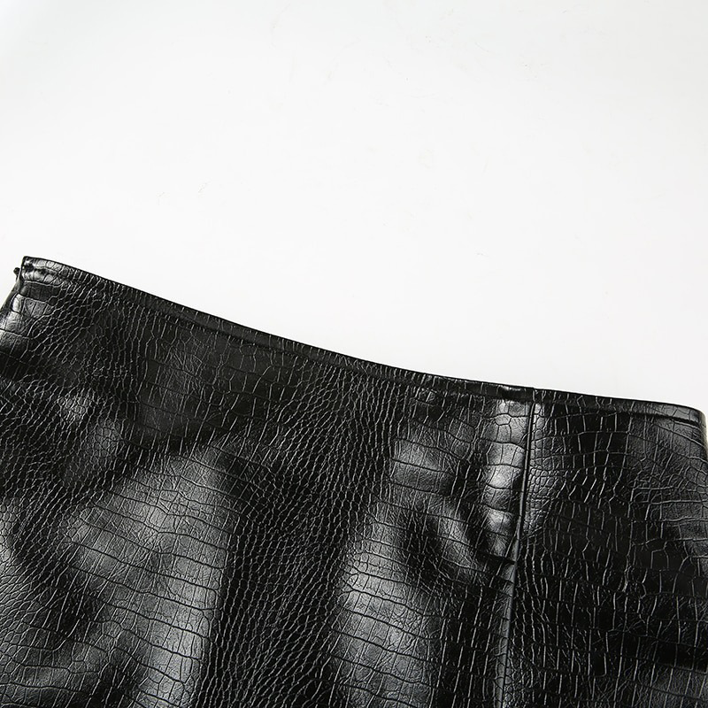 Close-up of a women's black mini PU leather skirt with a textured finish, showcasing the high waist design.
