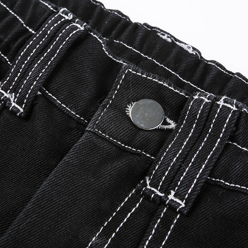 Close-up of women's black pants waistband with contrasting white stitching and button detail for a stylish streetwear look.