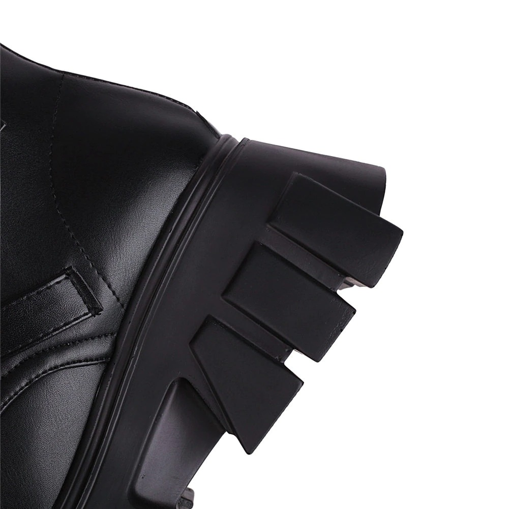Close-up of women's black platform boots featuring unique bat buckle detail and stylish chunky heel design.