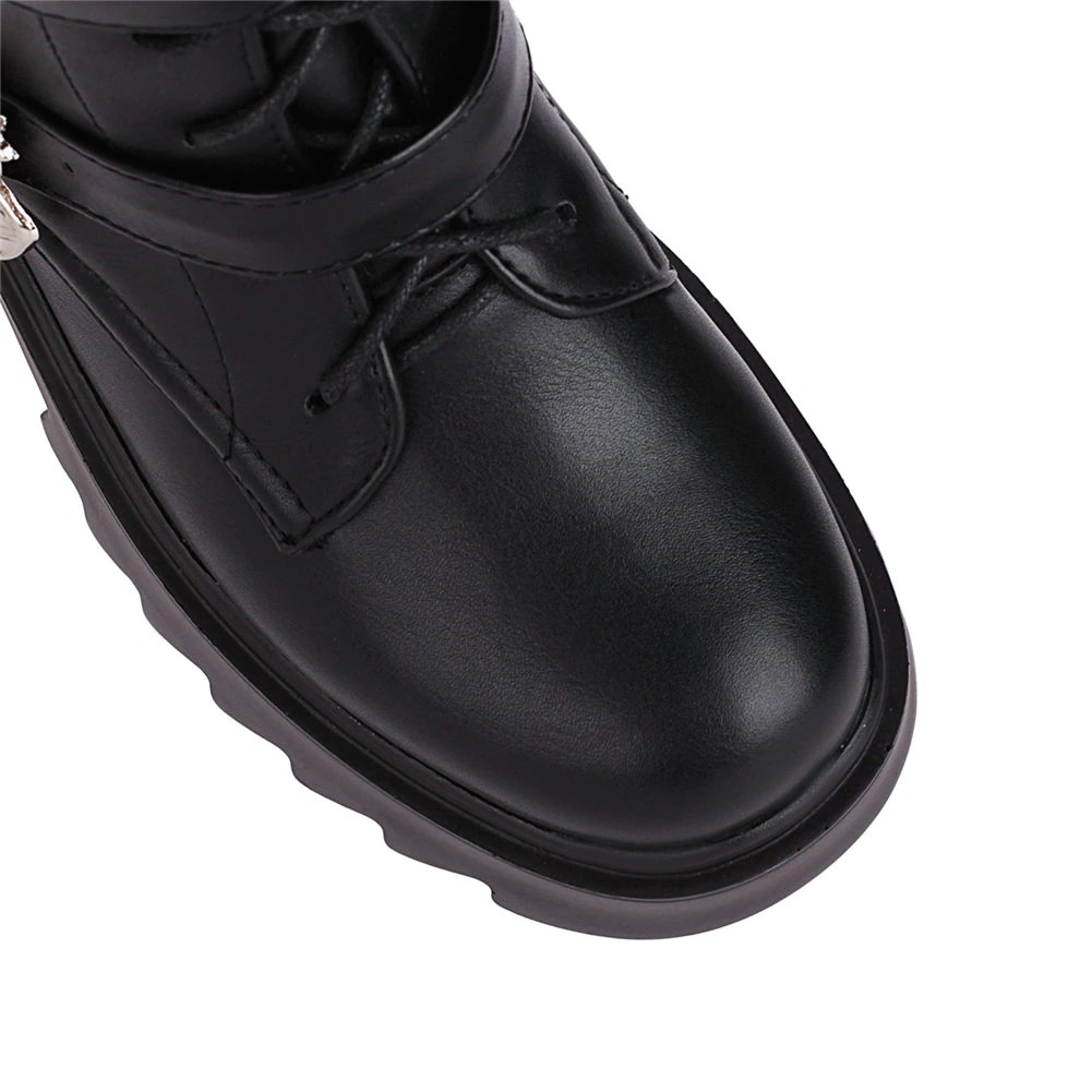 Close-up of women's black platform boots with bat buckles, showcasing stylish punk design and glossy patent leather finish.