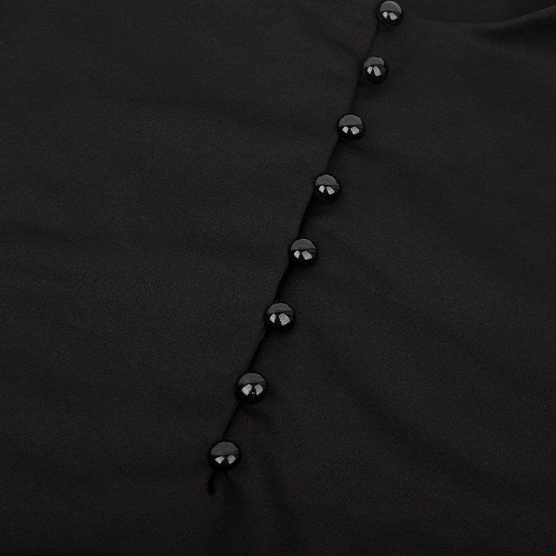 Close-up of black buttons on a gothic-style women's dress, adding elegance to the pleated fabric.