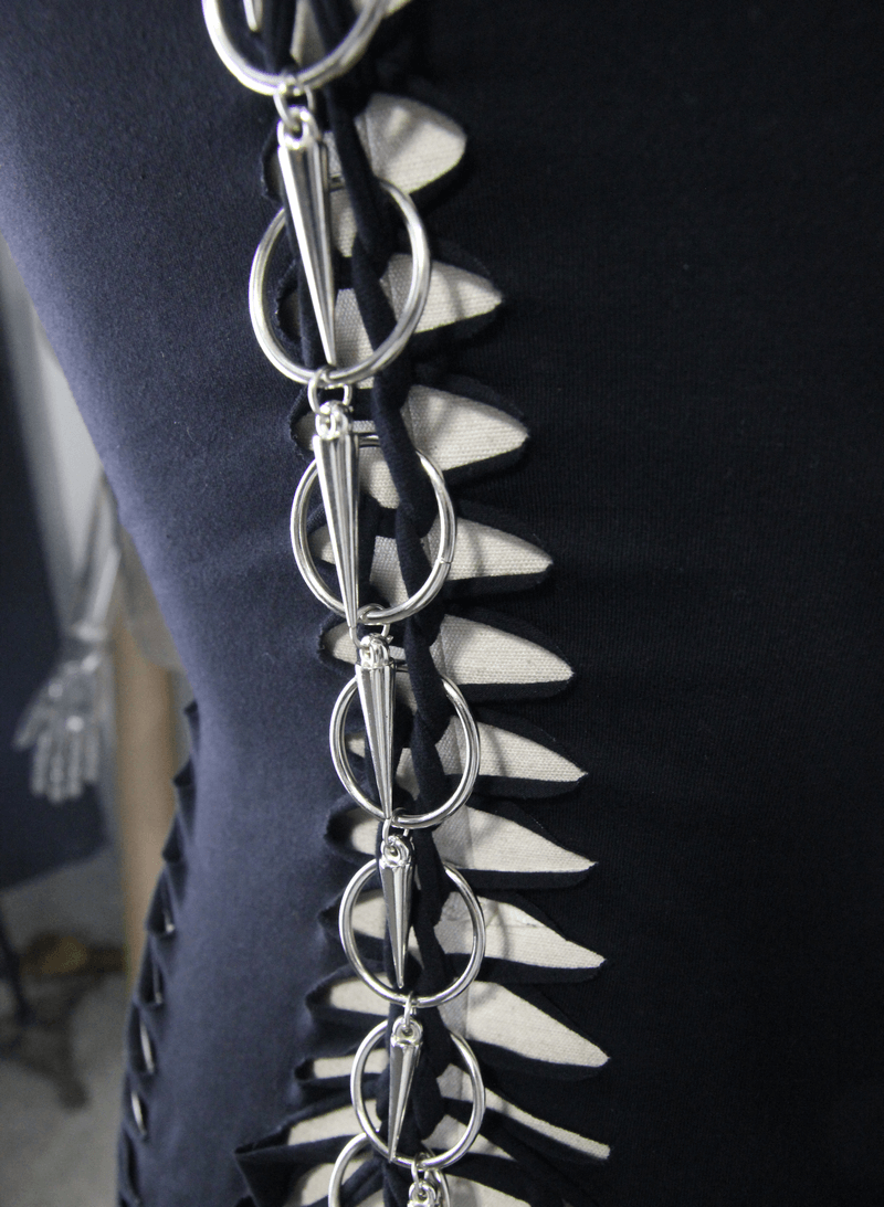Close-up of black tank top with ripped details and stylish rings at the back, showcasing gothic fashion.