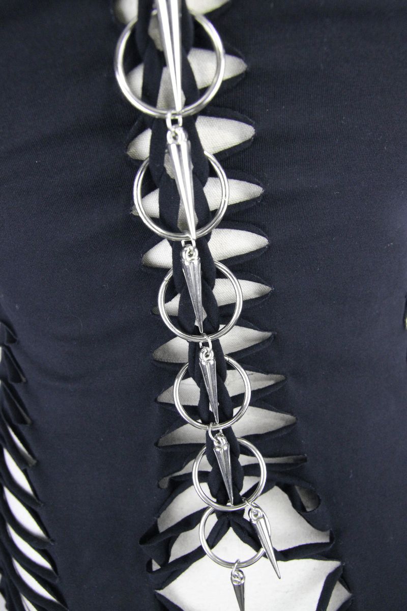 Close-up of silver rings and cut-out details on a women's black gothic tank top, showcasing edgy fashion design.