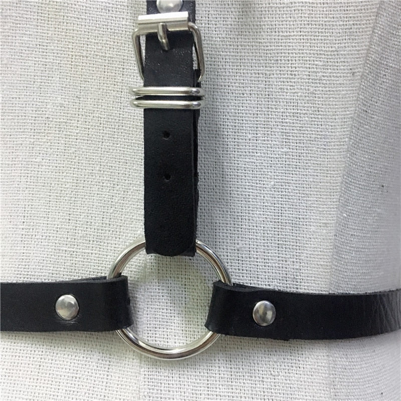 Close-up of a gothic body harness with silver ring detail and black straps, perfect for edgy fashion and cosplay.