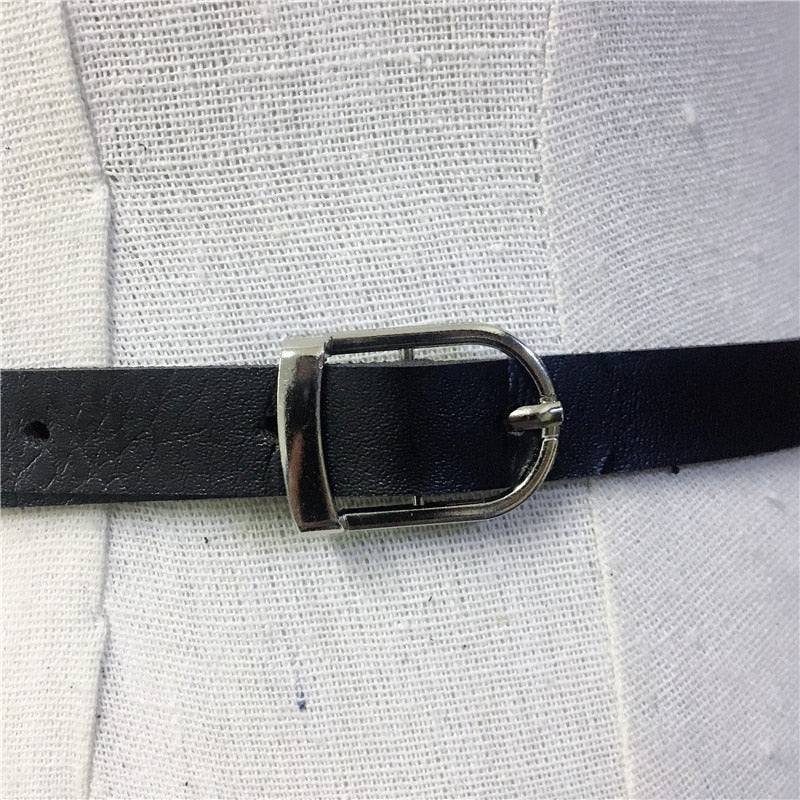 Close-up of a stylish black belt with a silver buckle, perfect accessory for gothic body harness outfits.