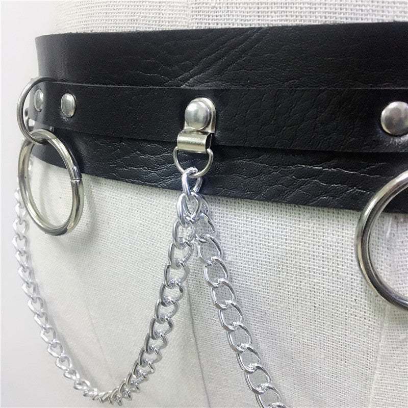 Close-up of a black leather body harness with silver chains and rings, perfect for gothic fashion and edgy looks.