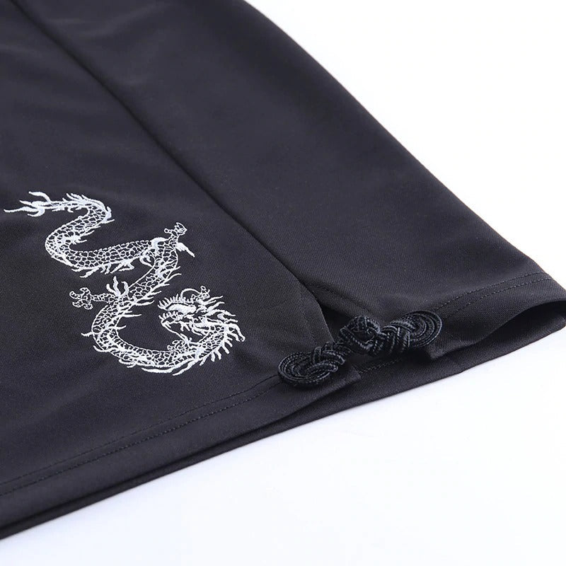 Close-up of black mini dress hem with intricate white dragon print and elegant detailing, perfect for gothic fashion.
