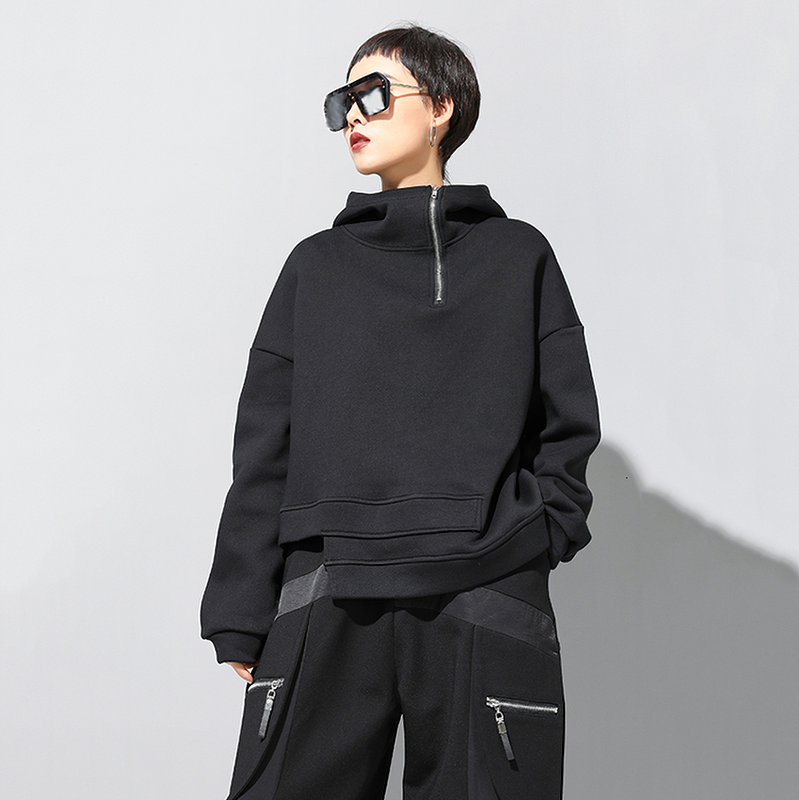 Stylish woman in a black oversized hoodie with a zipper, showcasing urban fashion and comfort.