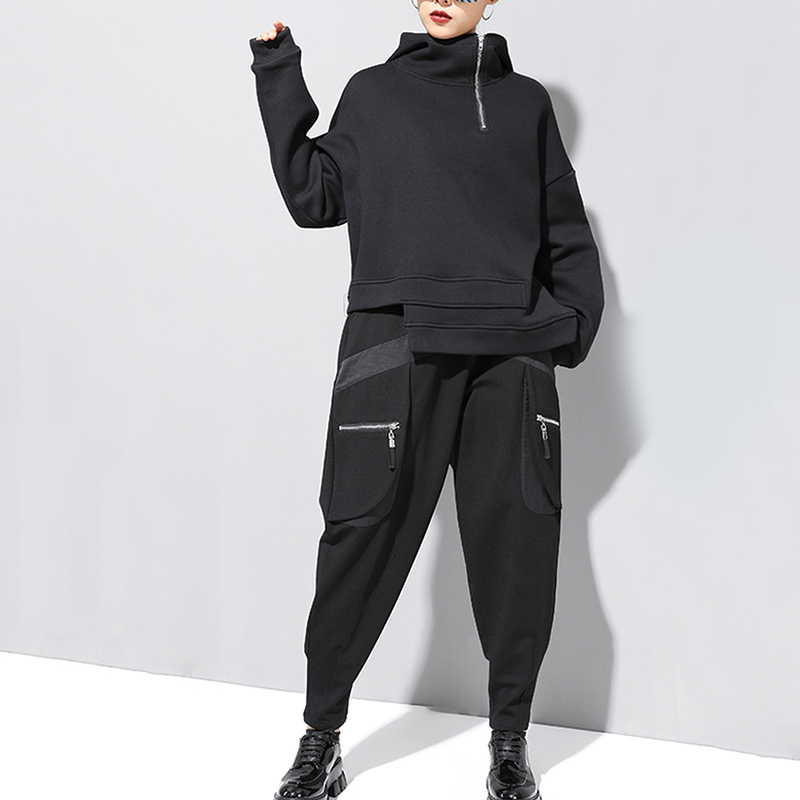 Stylish women's black oversized sweatshirt with high collar and zip detail, paired with trendy black pants for a chic look.
