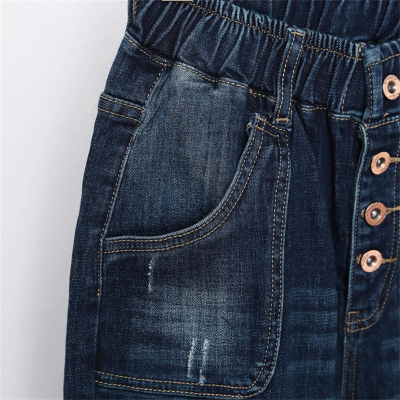 Close-up of women's fashion loose jeans featuring a high waist, pockets, and decorative buttons, in a blue denim finish.