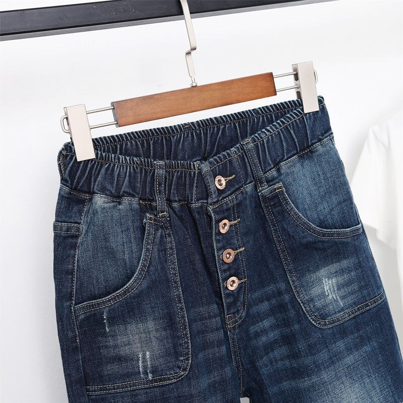 Close-up of women's fashion loose jeans in blue, featuring buttons and pockets, perfect for stylish streetwear.