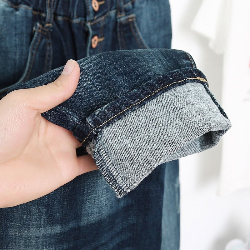 Close-up of rolled cuff of women's loose jeans, showcasing stylish denim and fabric details.