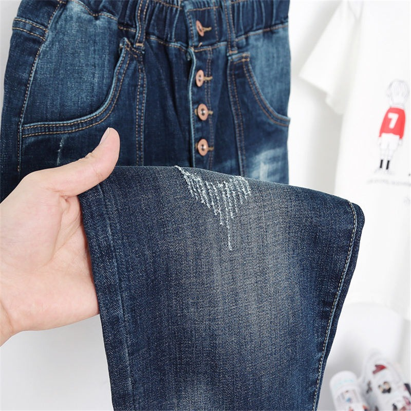 Close-up of women's high waist loose jeans in blue denim with buttons and stylish pocket detail.