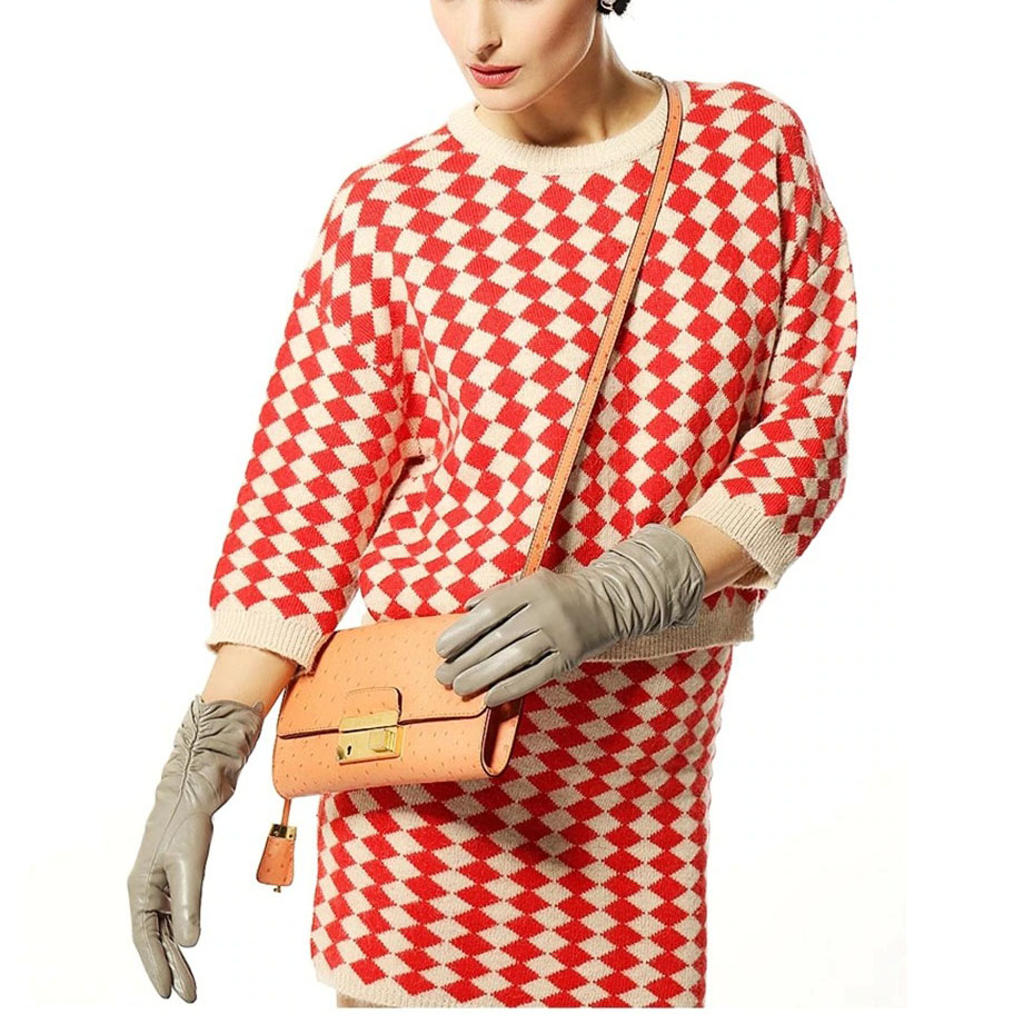 Stylish woman wearing red and white patterned outfit with gray leather gloves and orange handbag.
