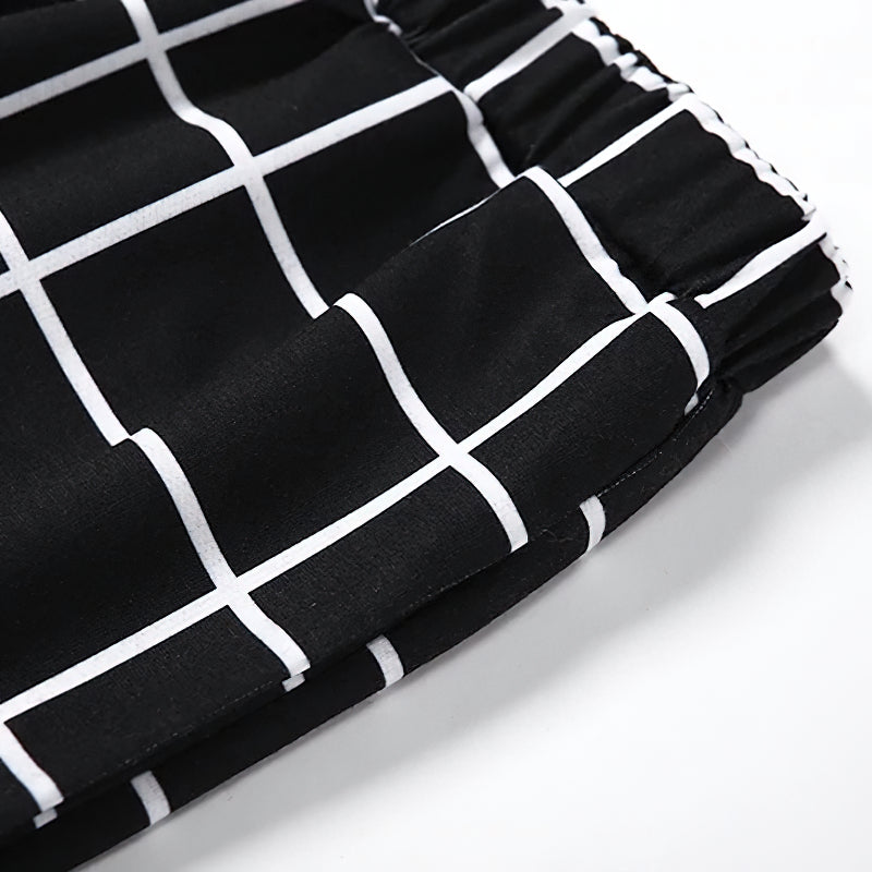 Close-up of women's gothic cargo pants featuring black-white checkerboard print and elastic waistband.