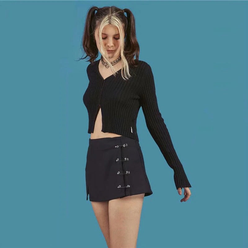 Stylish girl wearing a low waist black A-line short skirt with clips, paired with a cropped black sweater.