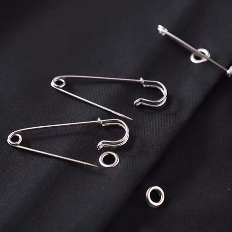 Silver safety pins on a black fabric, ideal for securing garments and adding a gothic touch to outfits.