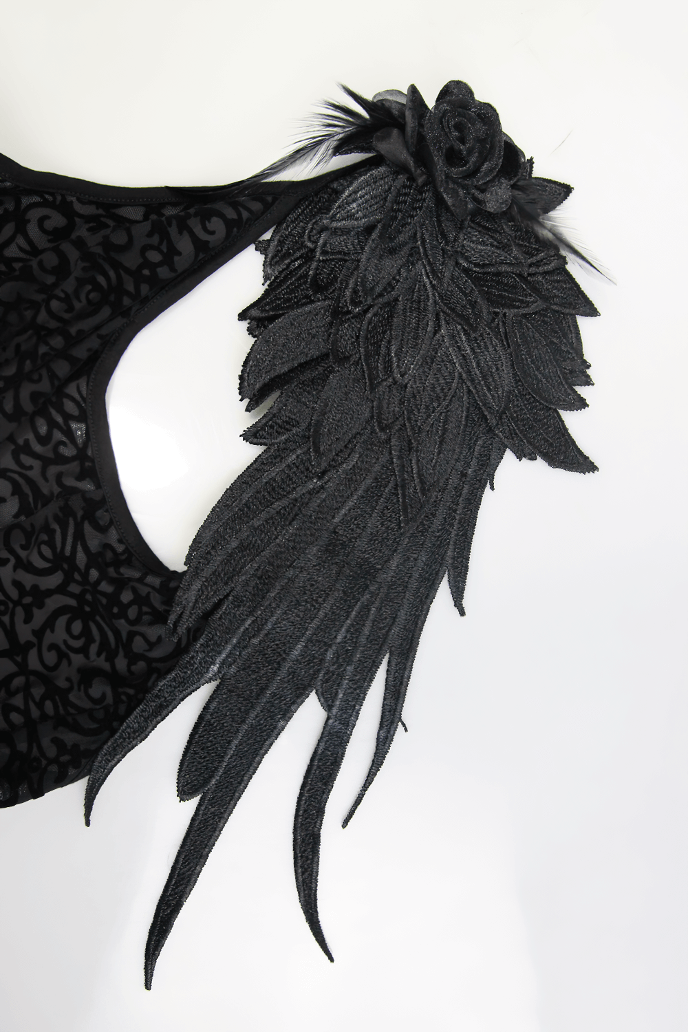Close-up of intricate black feather and floral design on a women's gothic dress shoulder.