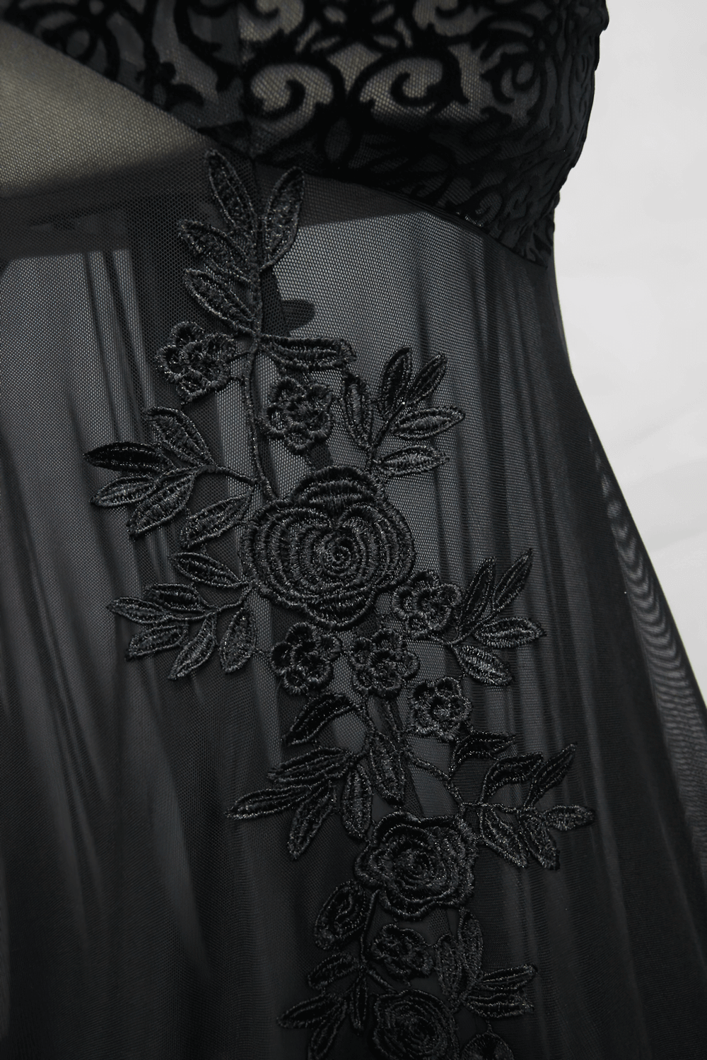 Close-up of elegant black embroidery on transparent fabric of a women's gothic long dress.