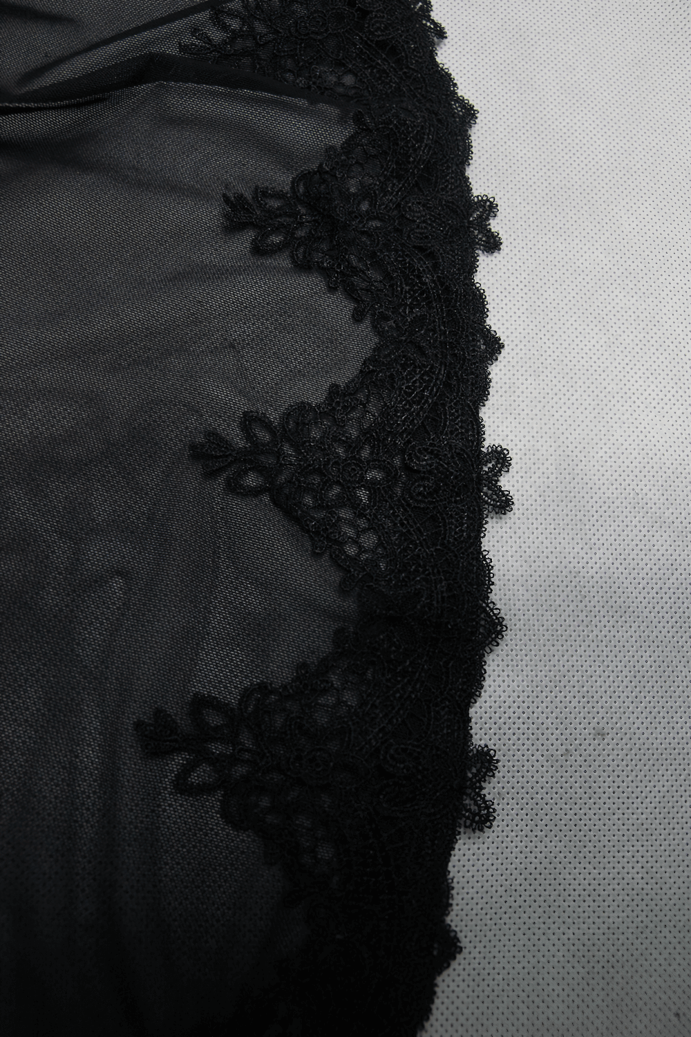 Close-up of elegant black lace detailing on a transparent gothic dress fabric.