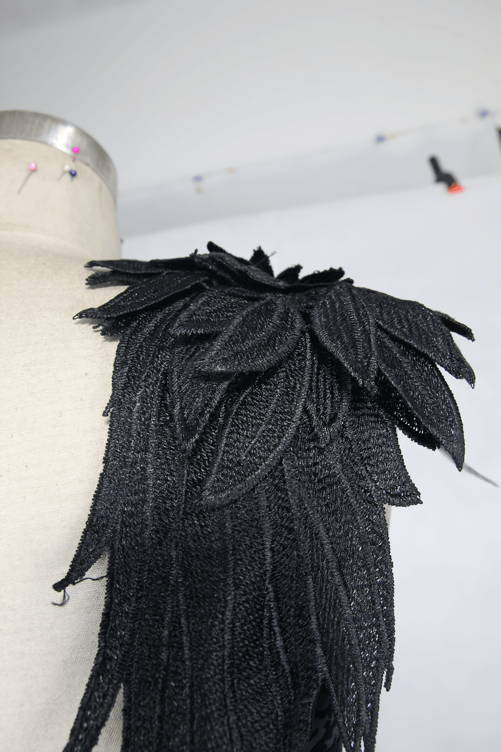 Close-up of intricate black fabric detailing on a gothic dress showcasing elegant leaf-like embellishments.