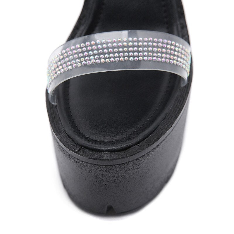 Close-up of elegant women's heeled sandals with rhinestone strap on black platform sole.